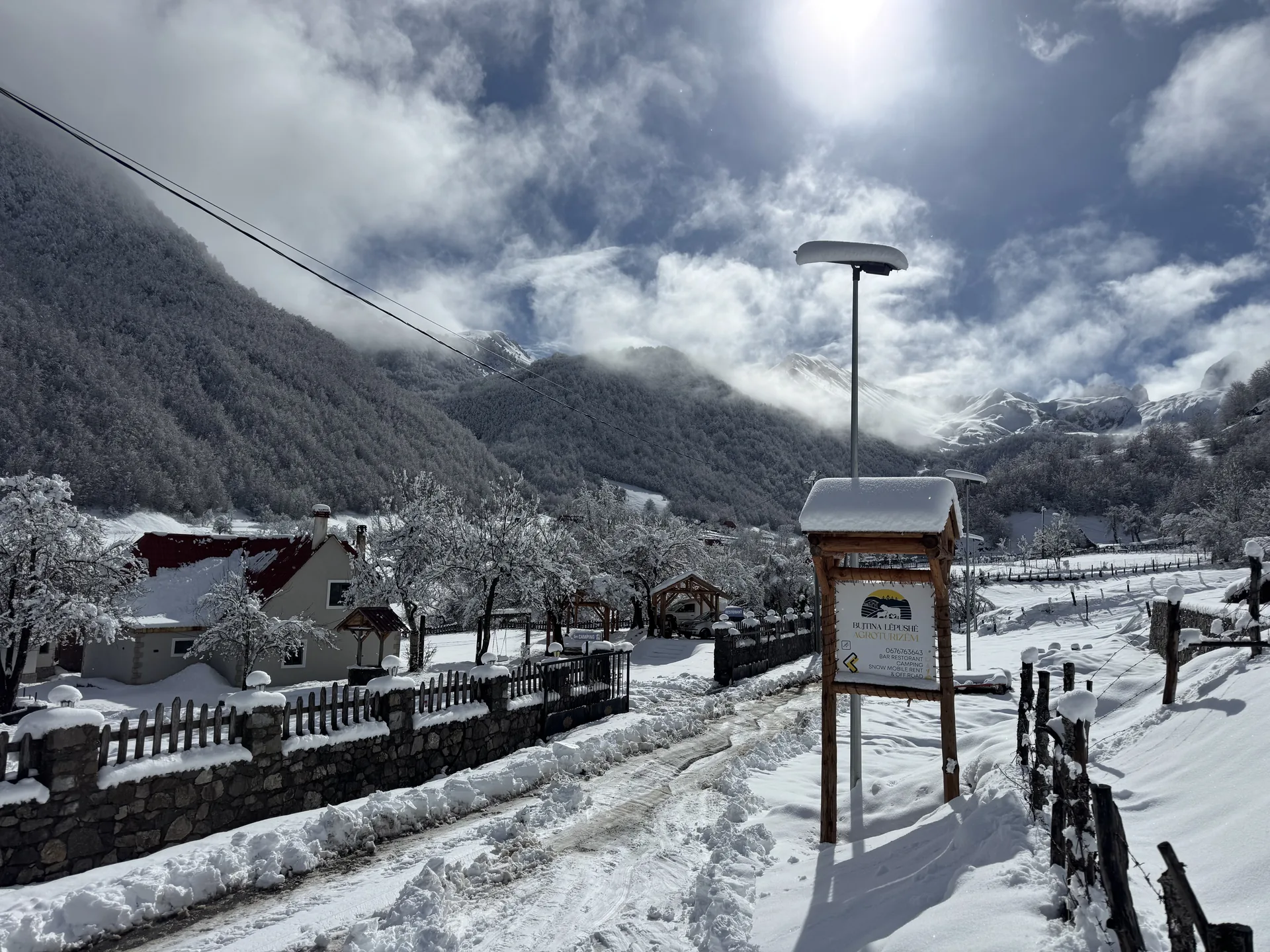 Hyrja e Bujtinës Lëpushë në dimër, me tabelën dhe majat e mbuluara me borë